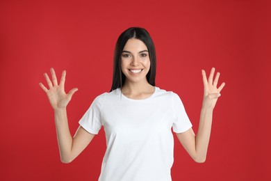 Woman showing number nine with her hands on red background