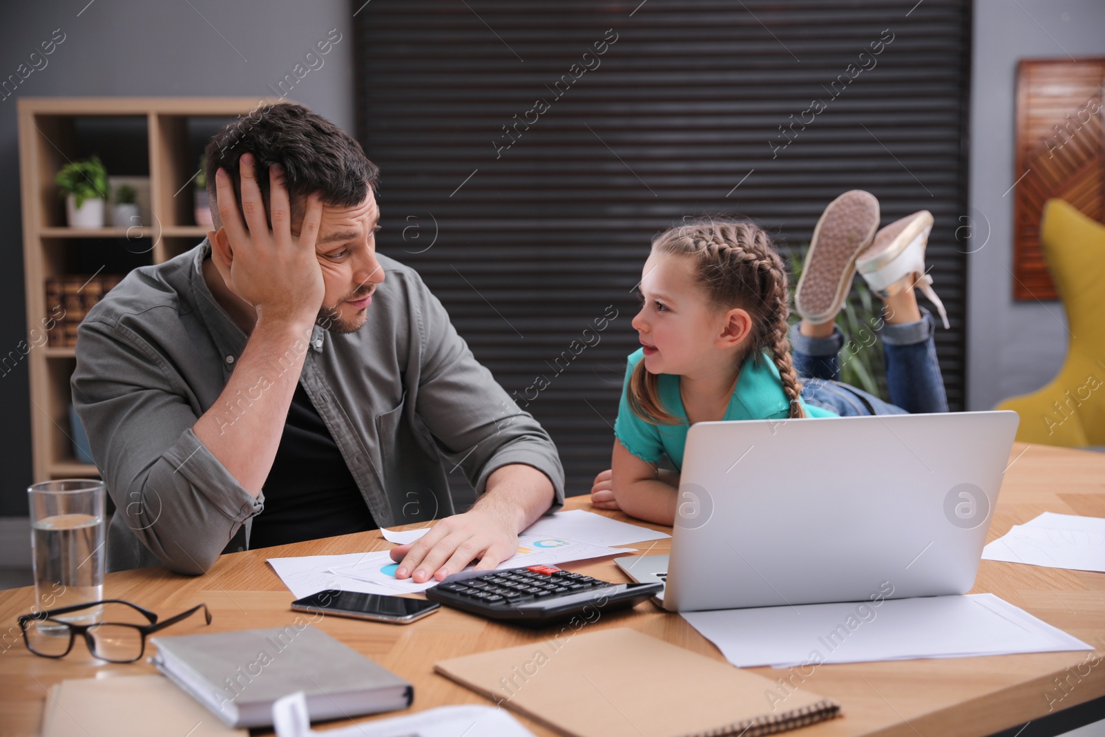 Photo of Overwhelmed man combining parenting and work at home