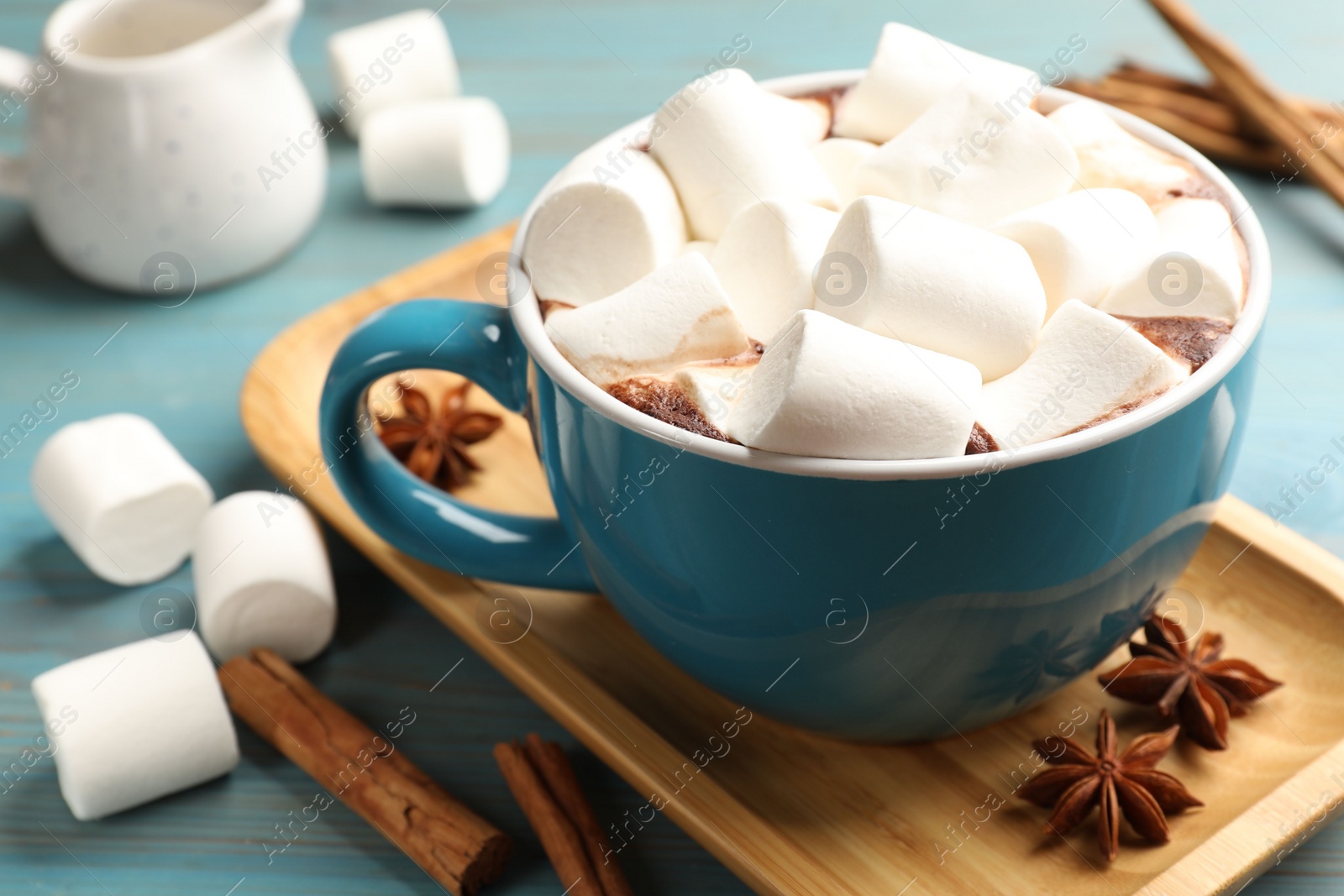 Photo of Tasty hot chocolate with marshmallows on light blue wooden table, closeup