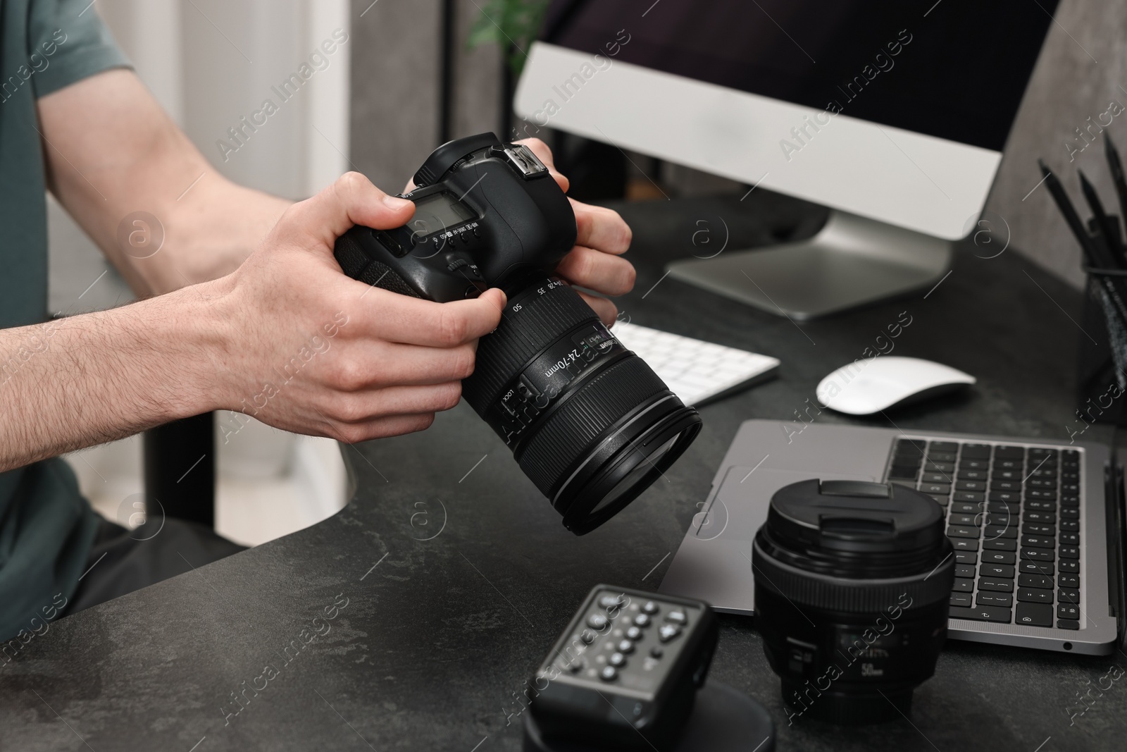 Photo of Photographer holding camera at dark table, closeup