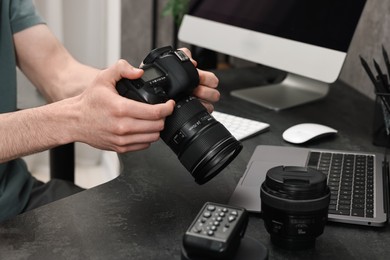 Photo of Photographer holding camera at dark table, closeup