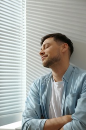 Photo of Handsome man near window with Venetian blinds