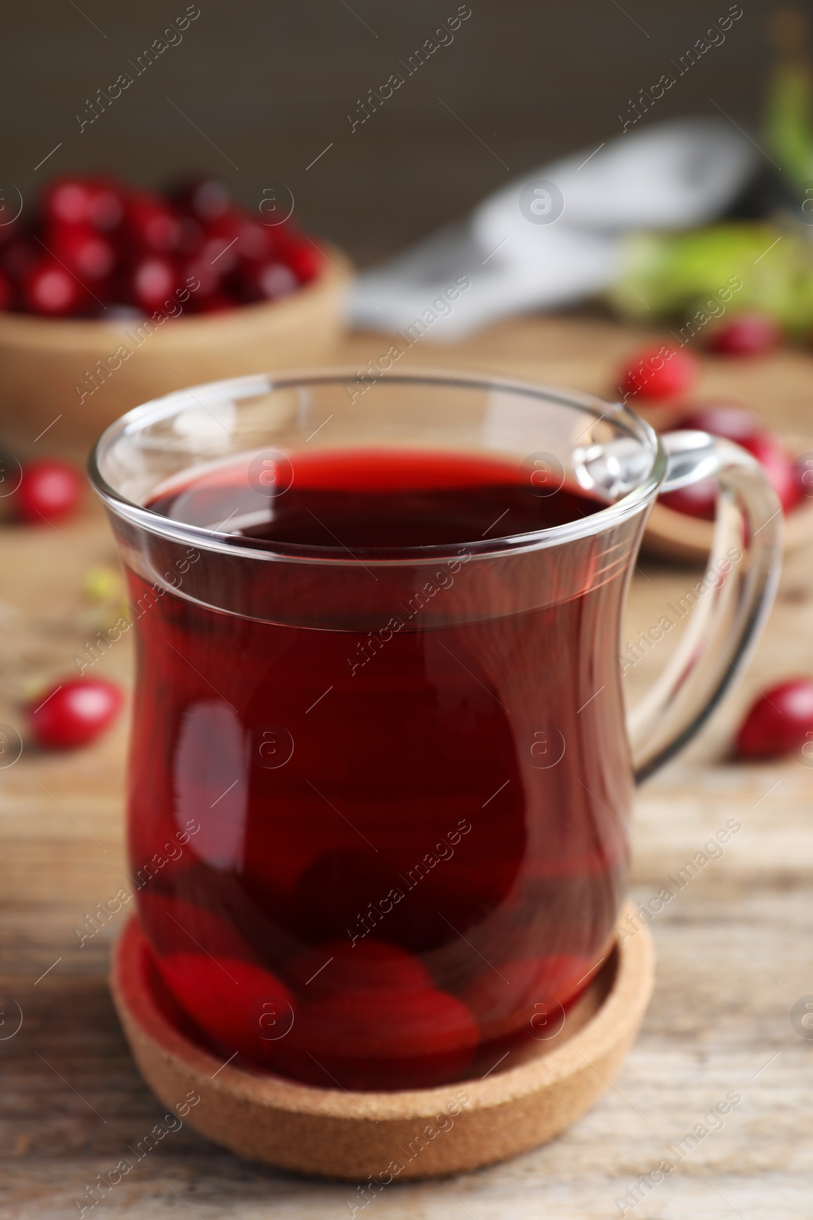 Photo of Glass cup of fresh dogwood tea with berries on wooden table