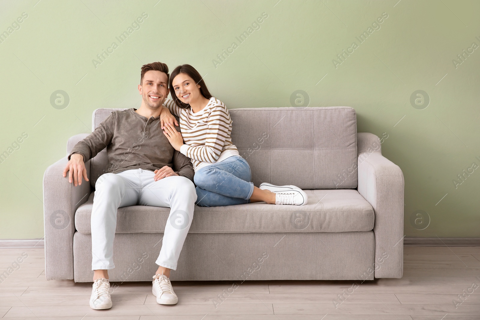 Photo of Happy young couple sitting on sofa at home