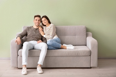 Happy young couple sitting on sofa at home