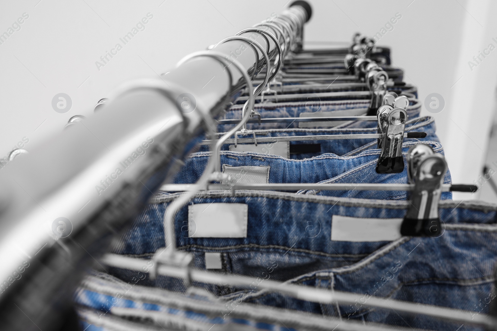 Photo of Rack with different jeans on light background, closeup