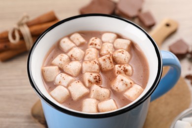 Photo of Cup of aromatic hot chocolate with marshmallows and cocoa powder on table, closeup