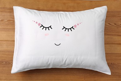Image of Soft pillow with cute face on wooden background, top view
