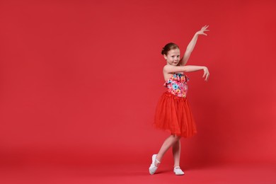 Cute little girl dancing on red background, space for text