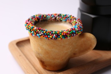 Delicious edible biscuit cup decorated with sprinkles on white background, closeup