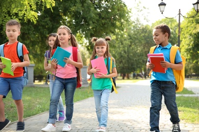 Photo of Cute little children with backpacks going to school