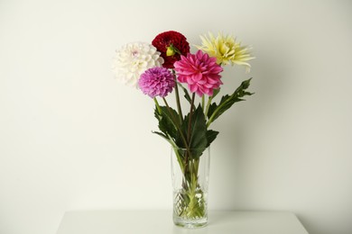 Photo of Bouquet of beautiful Dahlia flowers in vase on white table