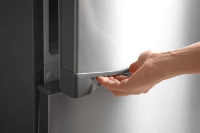 Woman opening modern refrigerator door, closeup view