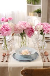 Photo of Stylish table setting with beautiful peonies and golden cutlery indoors