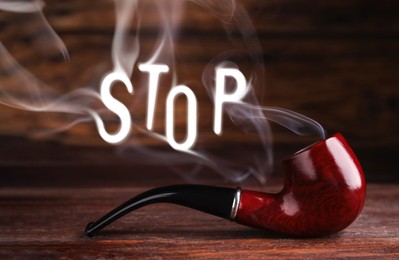 Image of Quit smoking. Word Stop of smoke and tobacco pipe on wooden table
