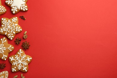 Photo of Tasty star shaped Christmas cookies with icing and spices on red background, flat lay. Space for text