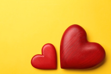 Photo of Red wooden hearts on yellow background, flat lay. Space for text