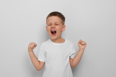Photo of Angry little boy screaming on white background. Aggressive behavior