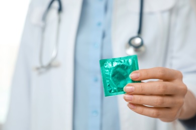 Photo of Female doctor holding condom, closeup. Safe sex concept