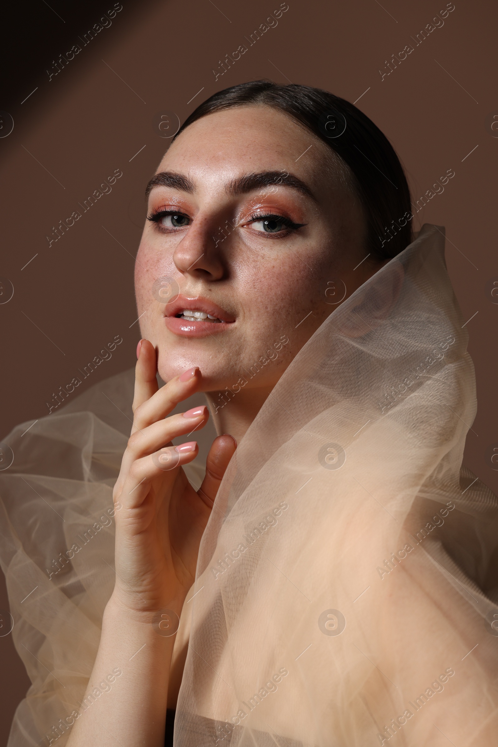 Photo of Fashionable portrait of beautiful woman with fake freckles on brown background