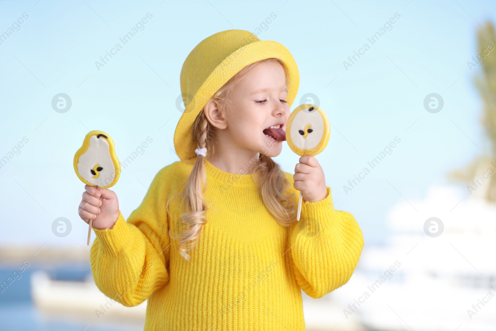 Photo of Cute little girl with tasty candies outdoors