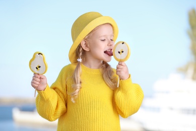 Photo of Cute little girl with tasty candies outdoors