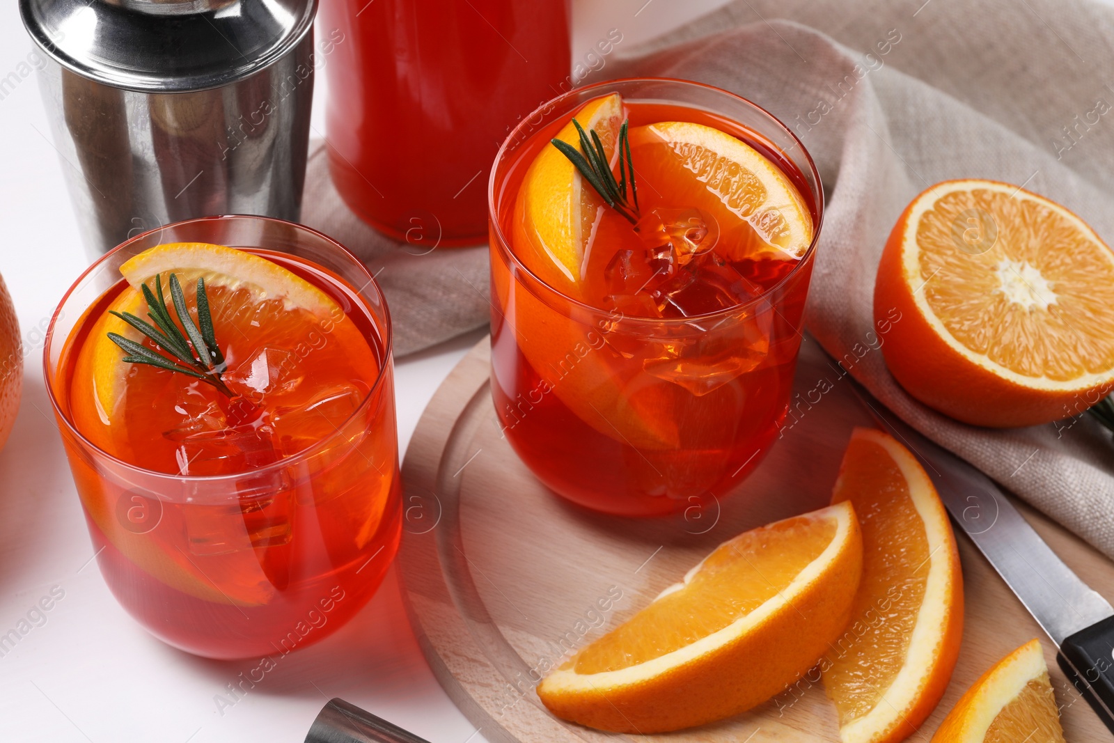 Photo of Aperol spritz cocktail, rosemary and orange slices on white wooden table