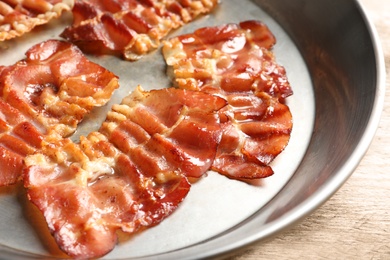 Frying pan with bacon on table, closeup