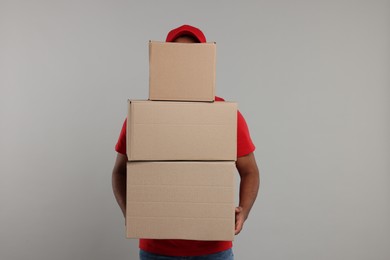 Courier with stack of parcels on grey background