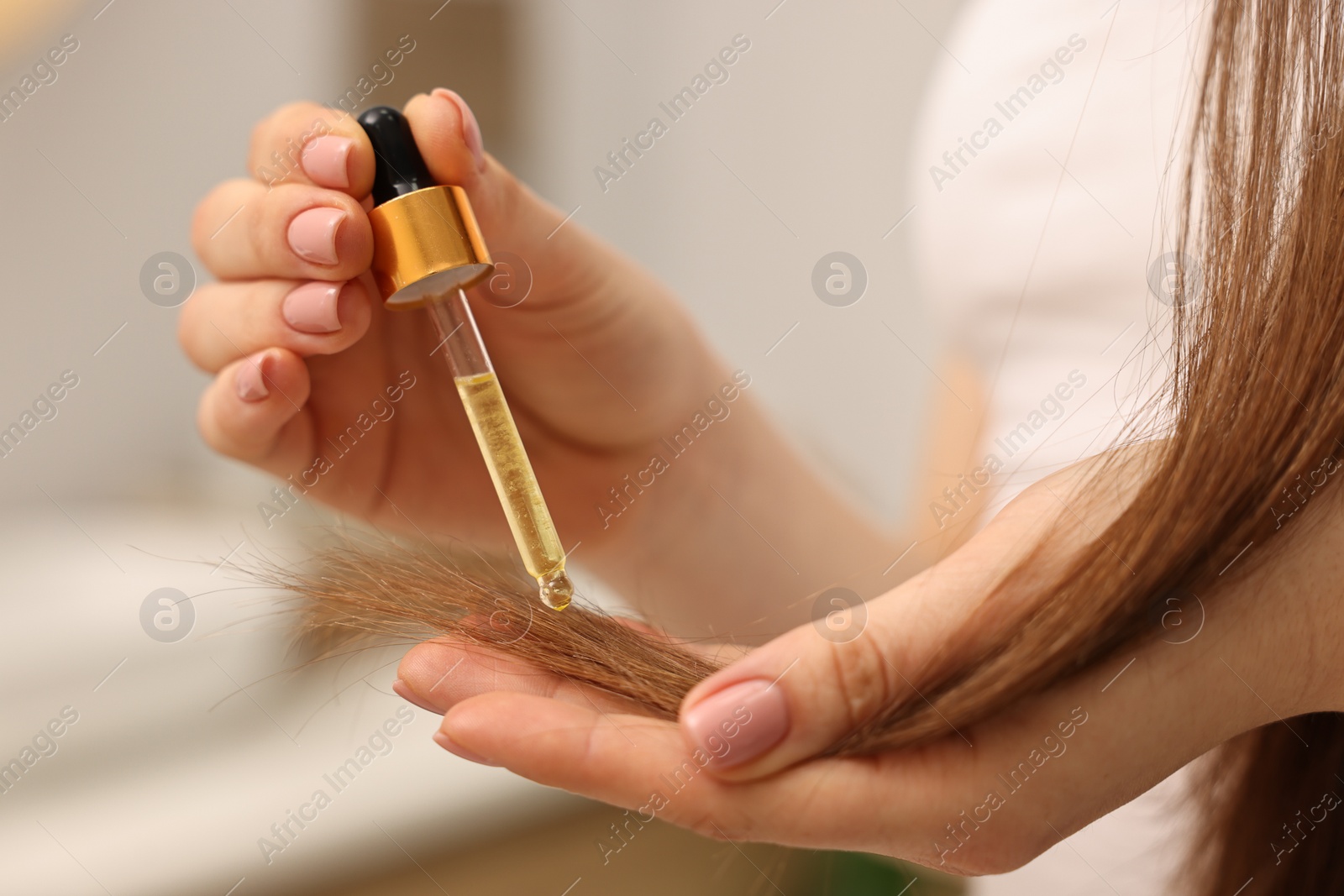 Photo of Woman applying oil hair mask indoors, closeup