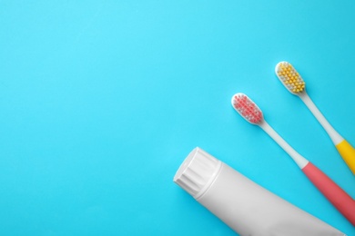 Photo of Blank tube of toothpaste and brushes on color background, top view with space for text