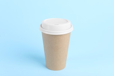 Photo of Paper cup with plastic lid on light blue background. Coffee to go