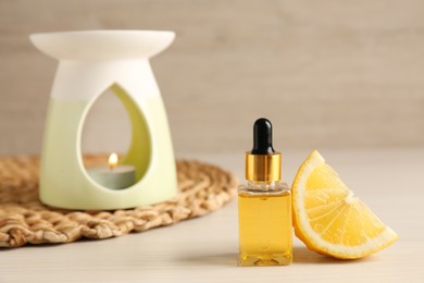 Photo of Aroma lamp, essential oil and lemon slice on wooden table. Space for text