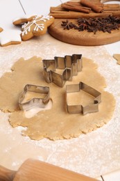 Photo of Making Christmas cookies. Raw dough, ingredients and cutters on white table