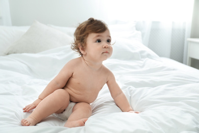 Photo of Cute little baby in diaper on bed