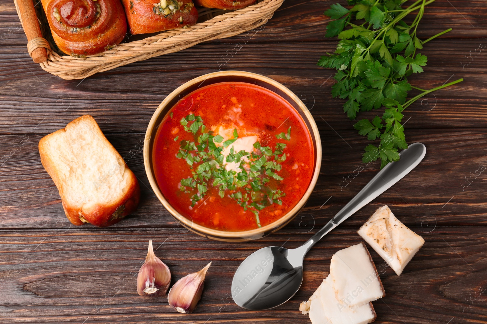 Photo of Delicious borsch served with pampushky and salo on wooden table, flat lay. Traditional Ukrainian cuisine