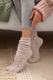 Woman wearing warm knitted socks at home, closeup