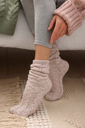 Photo of Woman wearing warm knitted socks at home, closeup