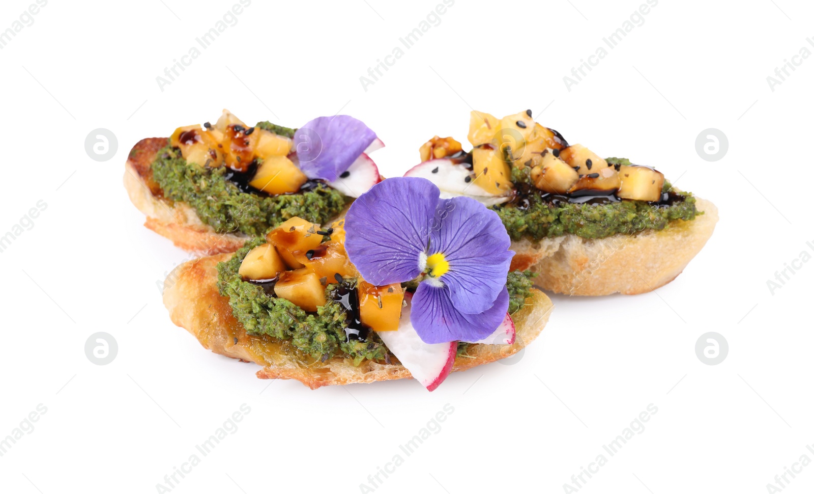 Photo of Delicious bruschettas with pesto sauce, tomatoes, balsamic vinegar and violet flower isolated on white