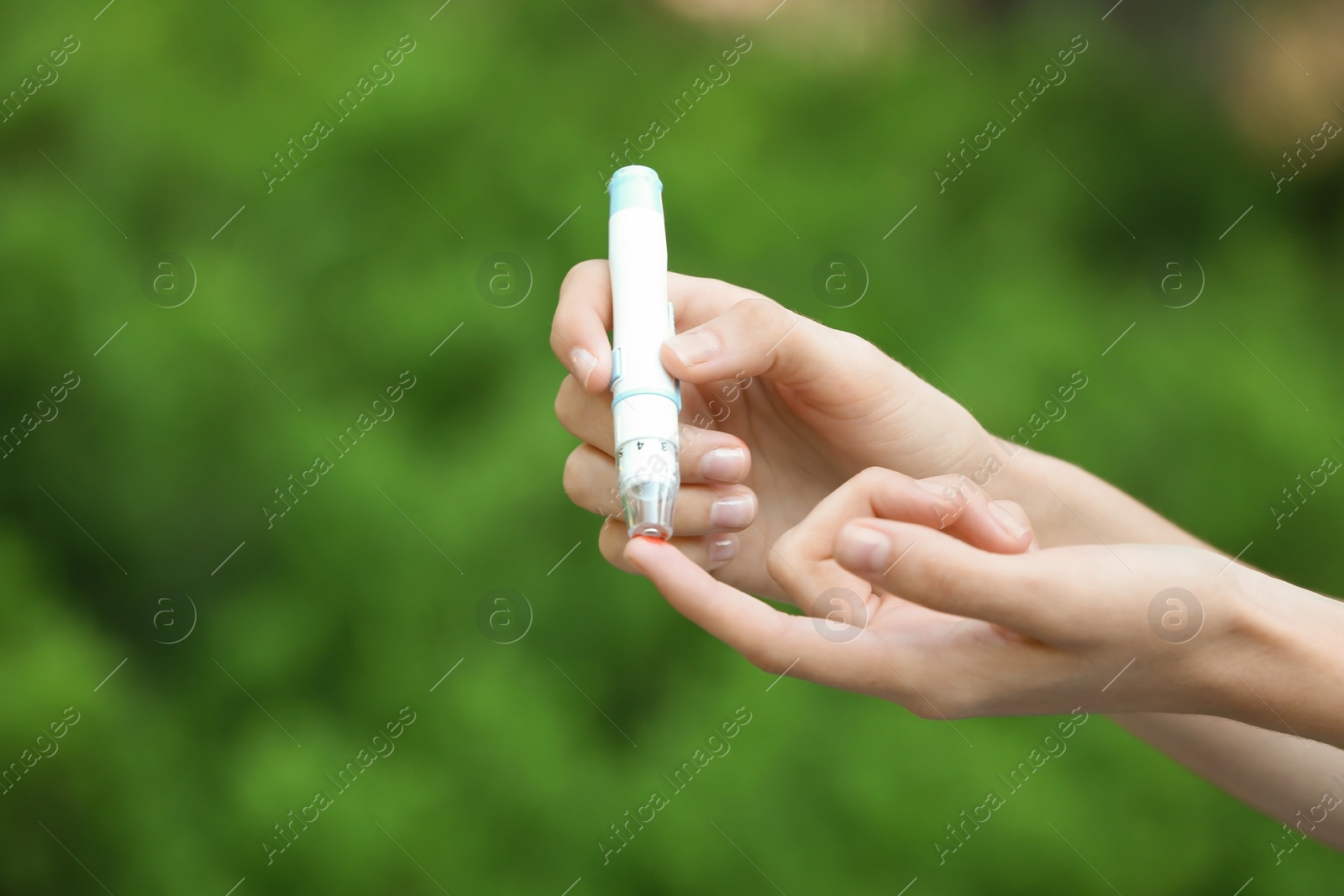 Photo of Woman using lancet pen on blurred background. Diabetes control