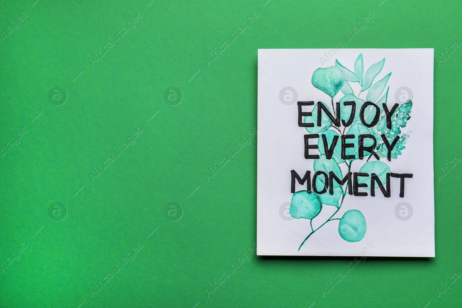 Photo of Card with beautiful phrase Enjoy Every Moment on green background, top view. Space for text