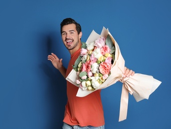 Photo of Young handsome man with beautiful flower bouquet on blue background