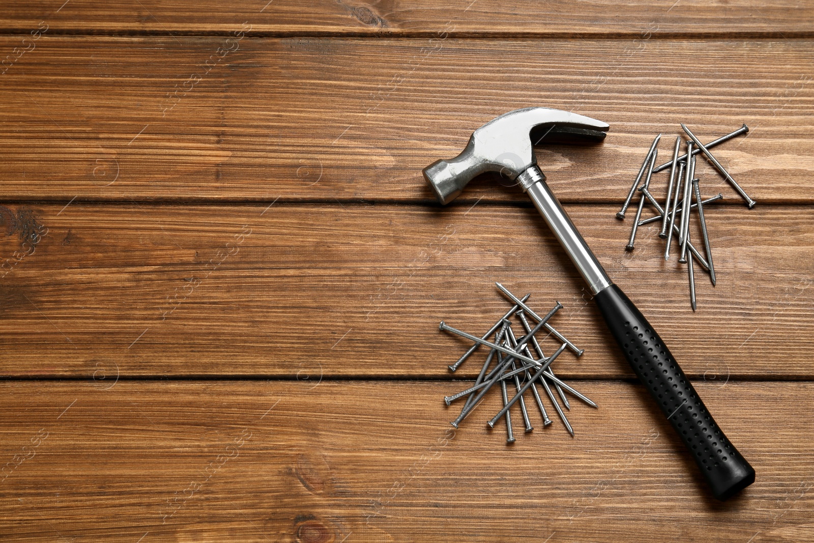 Photo of Hammer and metal nails on wooden table, flat lay. Space for text