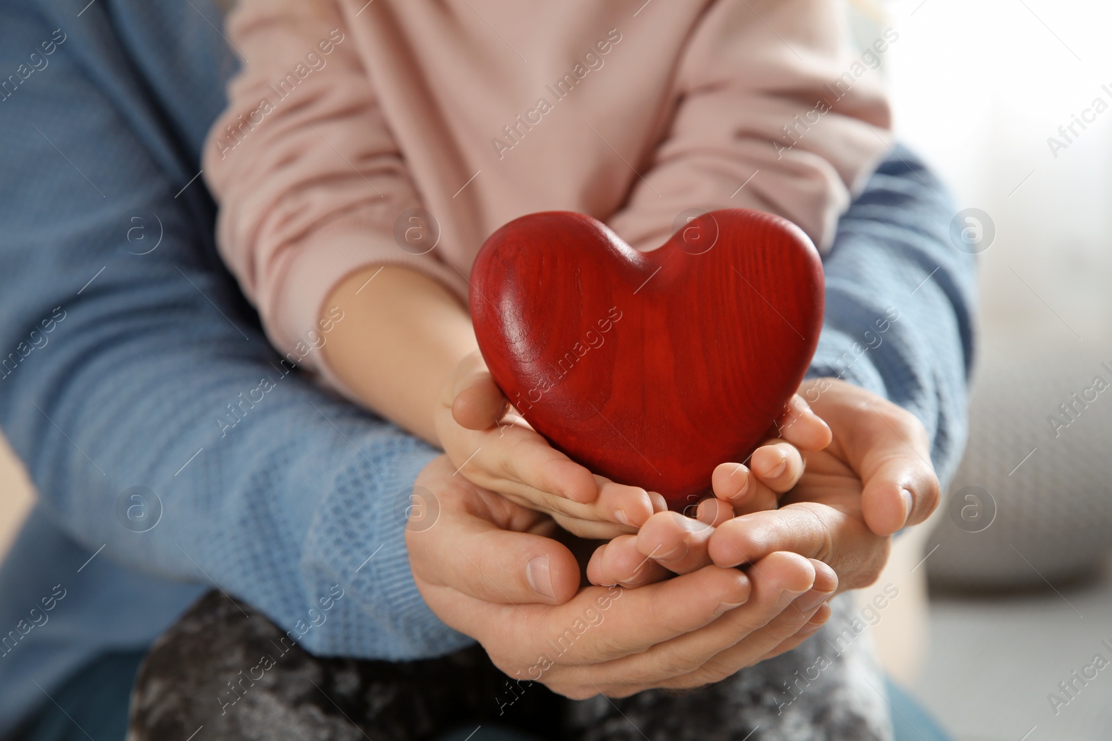 Photo of Man and his daughter holding red heart, closeup. Children's doctor