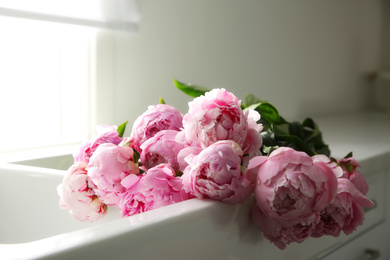 Photo of Bouquet of beautiful pink peonies in kitchen sink