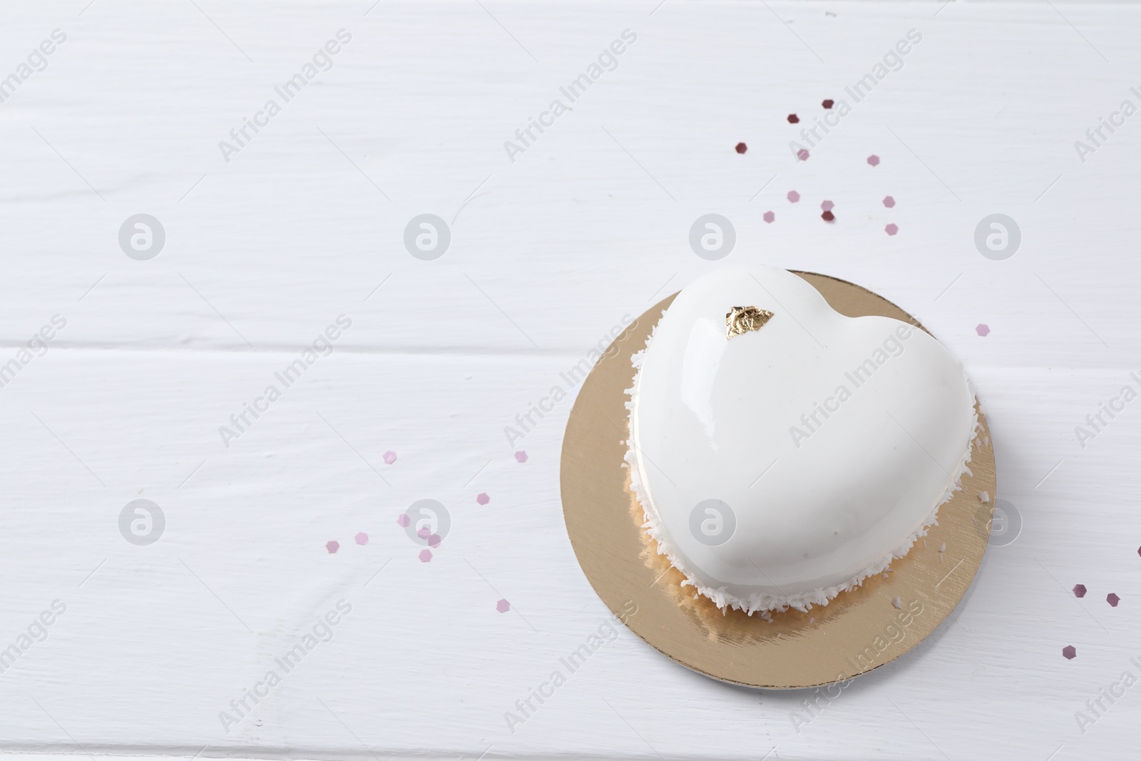 Photo of St. Valentine's Day. Delicious heart shaped cake and confetti on white wooden table, top view. Space for text