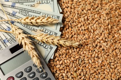 Photo of Dollar banknotes, calculator and wheat ears on grains, closeup. Agricultural business