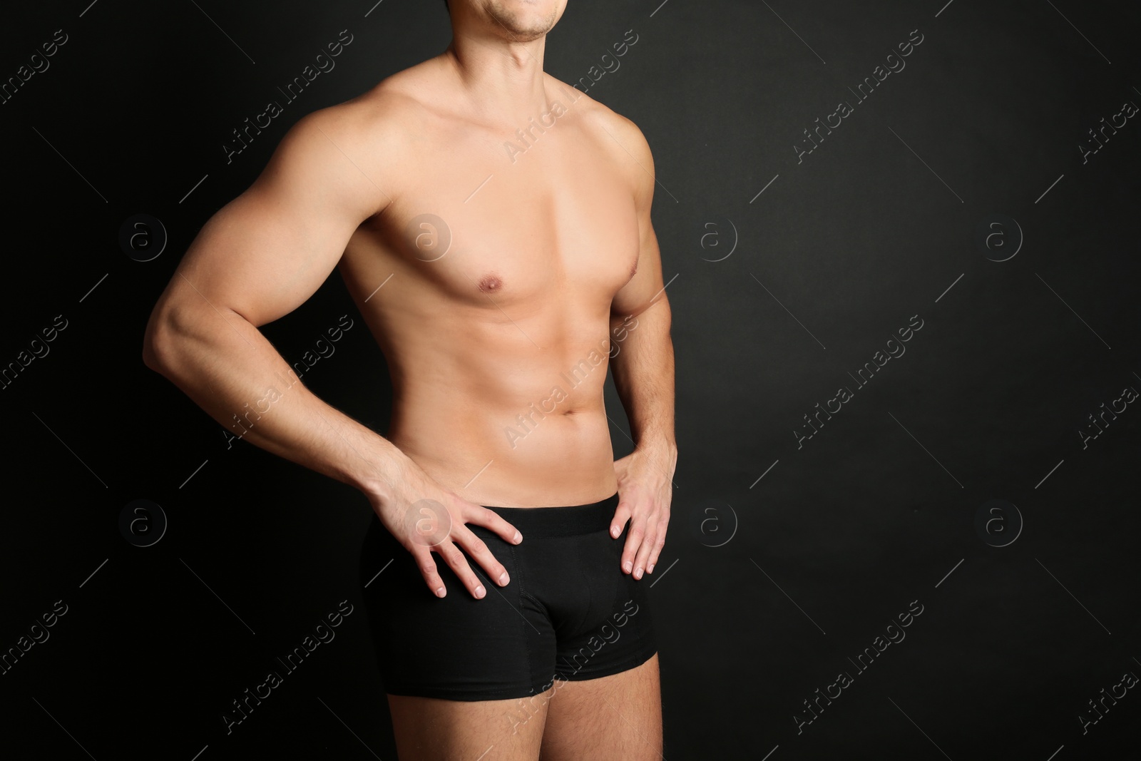 Photo of Man with sexy body on black background, closeup. Space for text