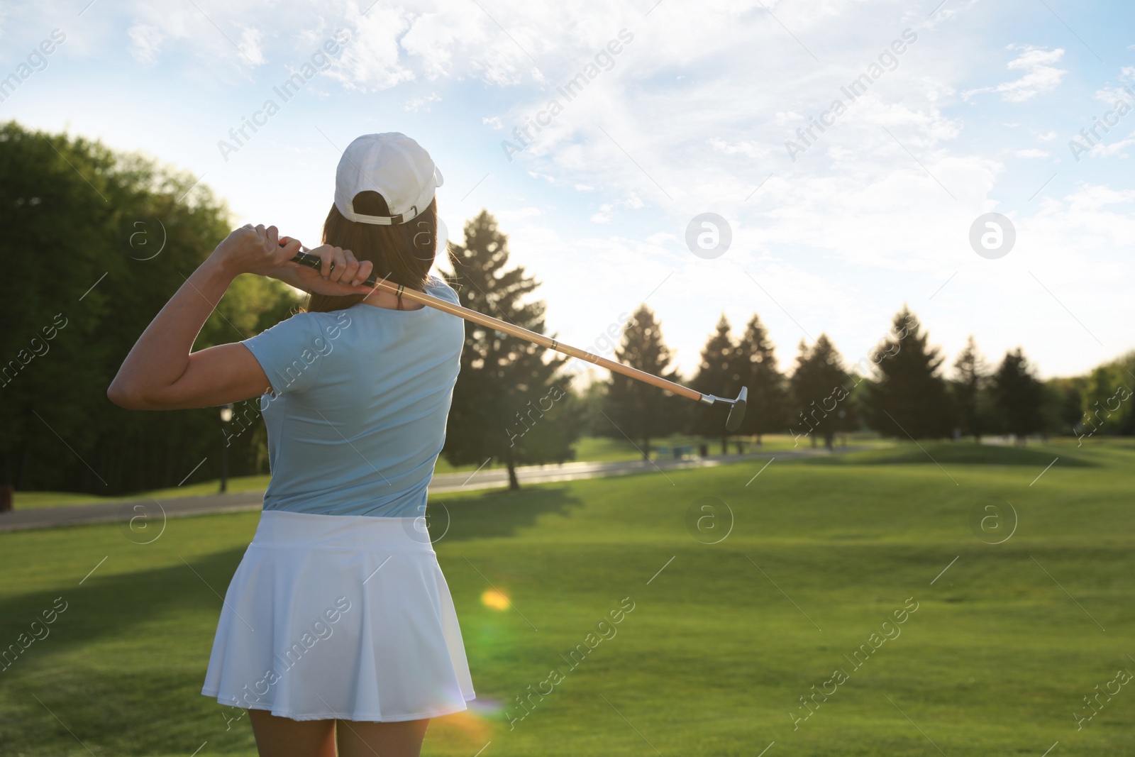 Photo of Woman playing golf on green course, back view