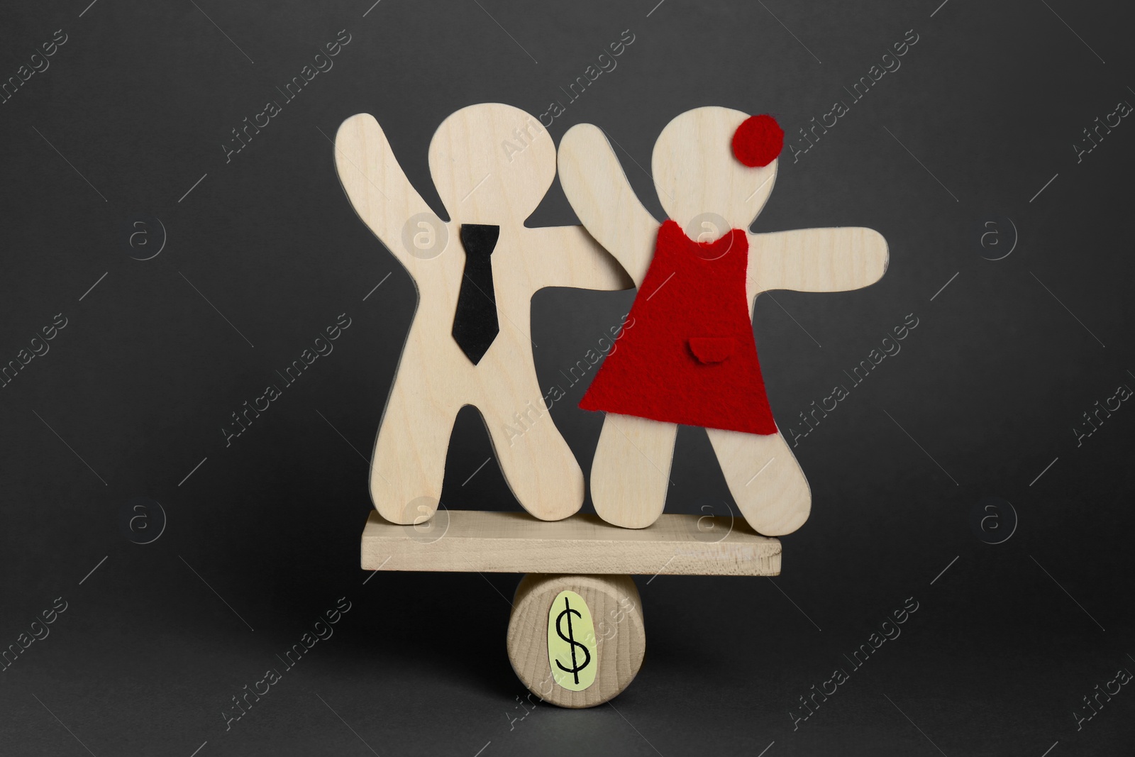 Photo of Gender pay gap. Wooden figures of man and woman on miniature seesaw against black background